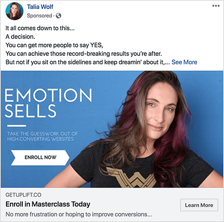 Ovo je snimka zaslona Facebook oglasa za masterclass Talije Wolf. U tekstu oglasa svaka je rečenica u zasebnom retku. Kaže „Sve se svodi na ovo... Odluka. Možete nagovoriti više ljudi da kažu DA. Možete postići one rekordne rezultate za kojima želite. Ali ne ako sjedite sa strane i nastavite sanjariti o tome... “Nakon ovog teksta nalazi se poveznica Vidi više. Slika oglasa ima plavu pozadinu s bijelim tekstom i sliku Talije od prsa prema gore. Ona je bijela žena smeđe i ljubičaste kose koja joj pada ispod ramena. Nosi crnu majicu sa zlatnim logotipom Wonder Woman. Tekst s lijeve strane njezine fotografije kaže "Emotion Sells" i "Uklonite nagađanja s web stranica s visokim konverzijama". Ispod ovog teksta nalazi se bijela strelica s crnim tekstom na kojoj stoji "Upišite se sada". Ispod slike nalazi se sljedeći naslov i tekst: "Getuplift.co" i "Upišite se na Masterclass Today" i "Nema više frustracije ili nadanja da ćete poboljšati konverzije". U donjem desnom kutu pojavljuje se gumb Saznajte više.