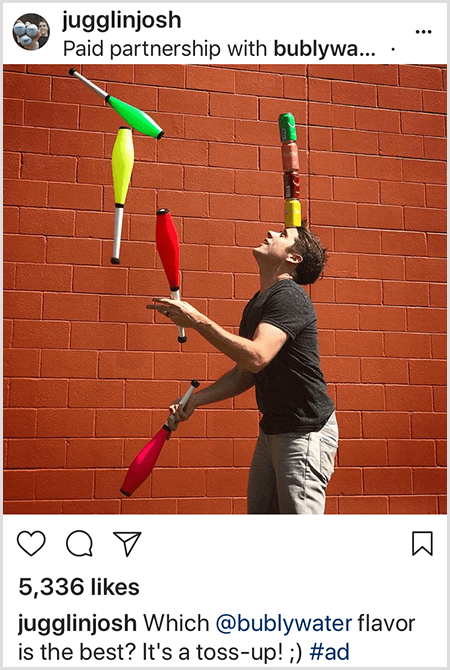 Josh Horton žonglira palicama koje se podudaraju s bojama četiri limenke vode Bubly složene na glavi. Pozadina je zid od crvene opeke. Fotografija je oglas koji je Josh stvorio za Bubly water i objavio ga u svom Instagram feedu s opisom Koji je okus Bubly Water najbolji? To je bacanje!
